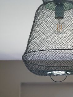 a bird feeder hanging from the ceiling with a light bulb in it's center