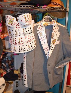 a suit and tie with playing cards on them are hanging from a rack in a closet