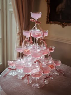 a table topped with lots of wine glasses filled with pink liquid and covered in bows