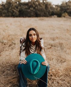 a woman sitting on the ground holding a green hat