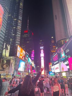 a crowd of people standing on top of a street next to tall buildings at night