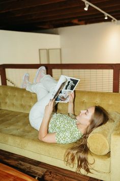 a woman laying on top of a couch reading a book