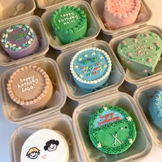 twelve decorated cupcakes in plastic containers on a table