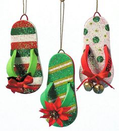 three christmas flip flops hanging from chains with bells on each ornament, decorated with green and red glitter