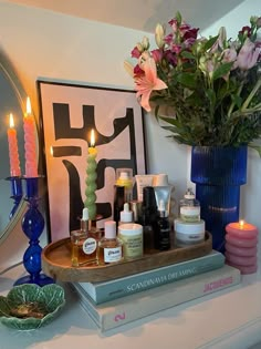 a table topped with candles and flowers on top of a book next to a mirror