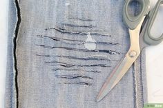 a pair of scissors sitting on top of a piece of fabric with holes in it