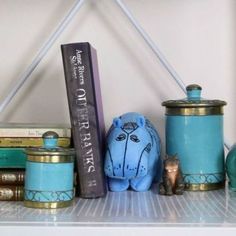 a shelf with books, jars and figurines on it's sides in front of a white wall