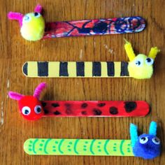 four different colored toothbrushes with faces and hair clips on top of a wooden table