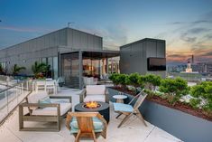 an outdoor patio with chairs, tables and fire pit on the top of a building