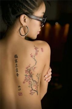 the back of a woman's body with tattoos on it