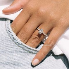 a close up of a person's hand with a diamond ring on their finger