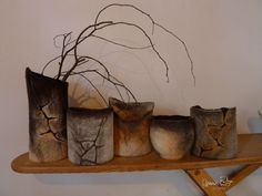 four vases are sitting on a shelf next to each other, with branches sticking out of them