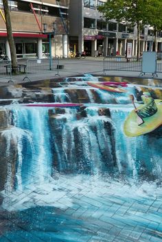 there is a painting on the ground that looks like it has a waterfall and a man riding a surfboard