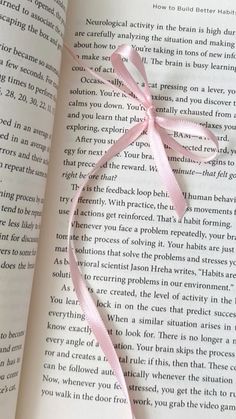 an open book with a pink ribbon on it