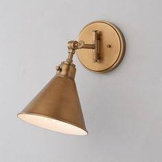 an antique brass wall light on a white wall