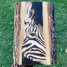 a zebra's face is painted on a piece of wood