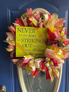 a baseball wreath with a sign on the front door saying, never let the fear of striking out keep you from playing the game