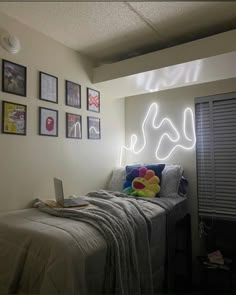 a bed with a laptop on top of it next to pictures hanging on the wall