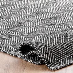 an area rug with black and white herringbones on the wood floor, close up