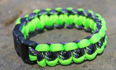 a neon green and black paracorine bracelet on top of a cement surface with a black buckle