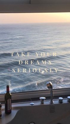 a bathroom sink sitting next to a window with the ocean in the background and a message written on it