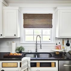 a kitchen with white cabinets and black counter tops, along with a stainless steel dishwasher