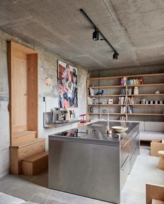 an industrial kitchen with stainless steel appliances and shelving in the back ground, surrounded by wooden bookshelves