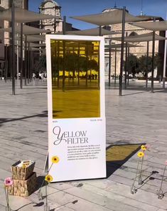 a large white sign sitting on the side of a road next to flowers and baskets