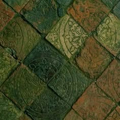 a close up view of an old brick floor with green and red tiles on it