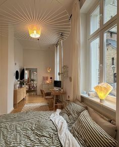 a bedroom with a bed, desk and television in the corner next to a large window