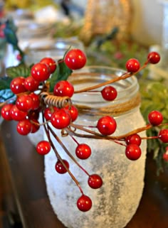 a jar filled with red berries sitting on top of a table next to other items