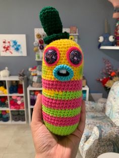 a hand holding up a crocheted cell phone case in the shape of a caterpillar