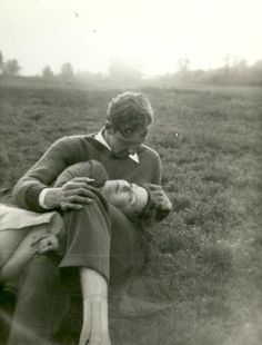 an old black and white photo with a man holding a woman's head in the grass