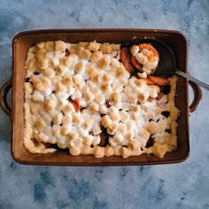 a casserole dish filled with marshmallows and other toppings next to a spoon