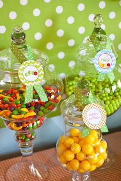 three glass jars filled with candy on top of a table next to green polka dot wall