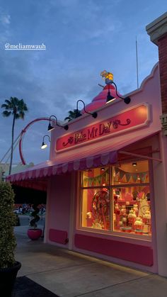 the front of a pink store with an amusement park theme in the background at dusk