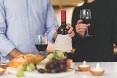 two people standing at a table with food and wine