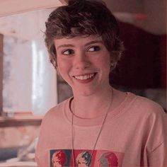 a young woman wearing a pink shirt and smiling at the camera