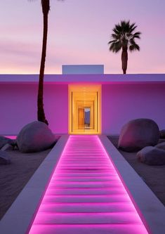 a pink building with stairs leading to it and palm trees in the background at dusk