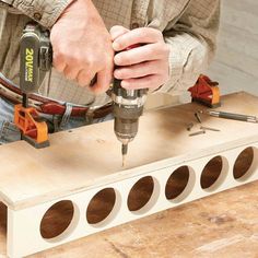 a man is using a drill to cut holes in the side of a piece of wood