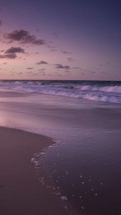 an ocean beach with waves coming in to the shore and some clouds above it at sunset