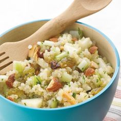 a blue bowl filled with rice and nuts next to a wooden spoon on a table