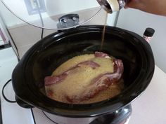 someone is pouring some liquid into a slow cooker with meat in the bowl on the stove