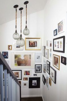 a staircase with pictures on the wall and hanging lights