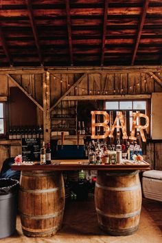 two wooden barrels sitting on top of a table next to a bar with the word bar spelled out