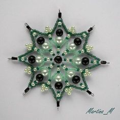 a green and white beaded snowflake ornament on a white background