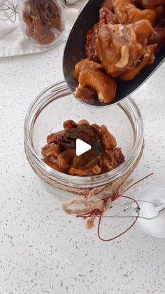 a glass bowl filled with nuts on top of a counter next to a white mouse