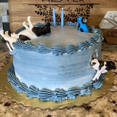 a cake with blue frosting and two dogs on the top is sitting on a table