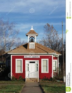 a red and white building with a clock tower on it's roof next to a sidewalk