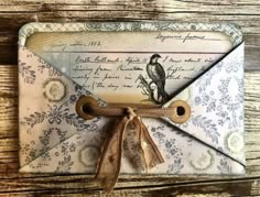 an envelope with a bird on it is tied to a wooden table and has a brown ribbon